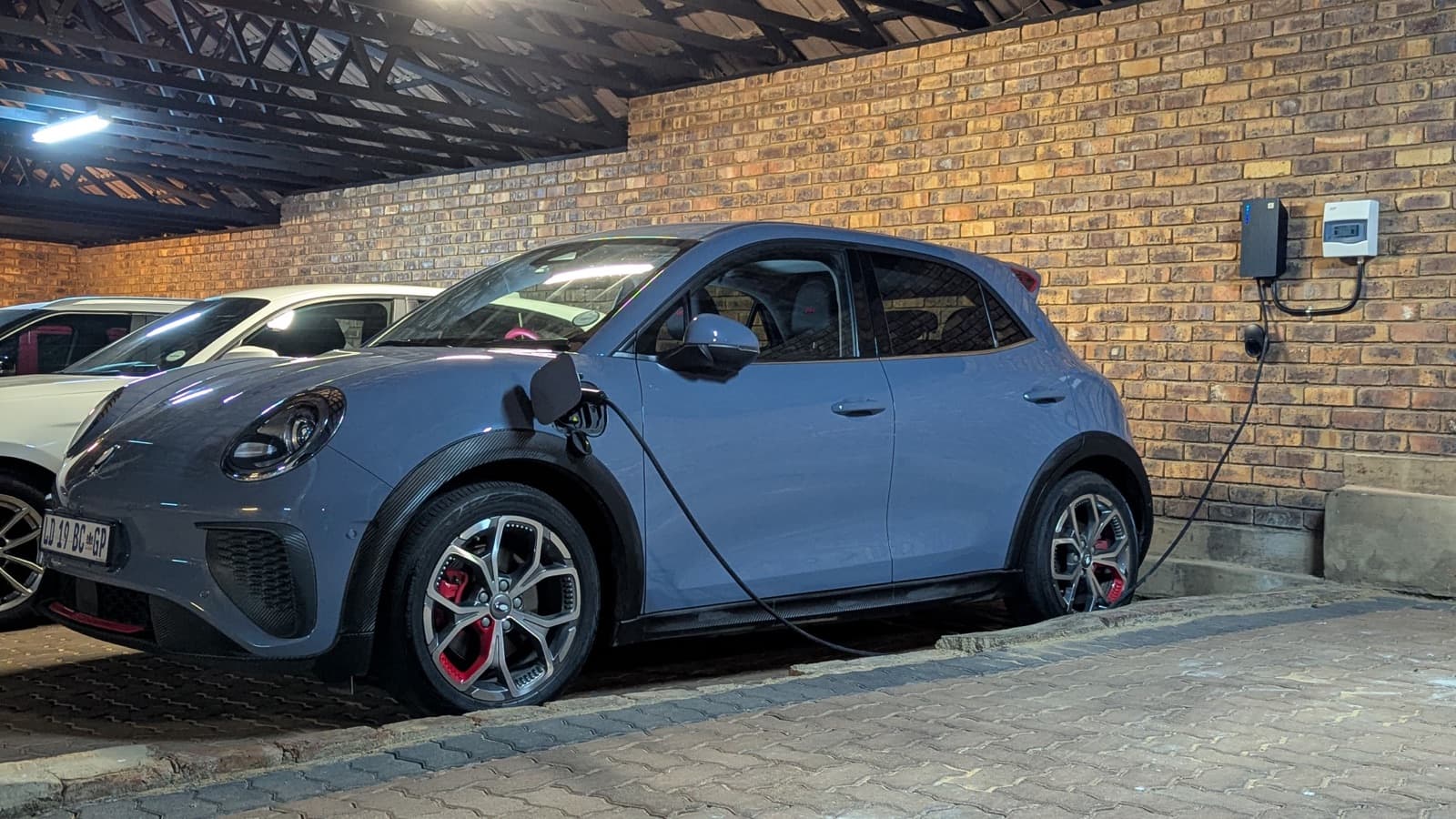 An EV charges from a wall-mounted TeltoCharge in a carport
