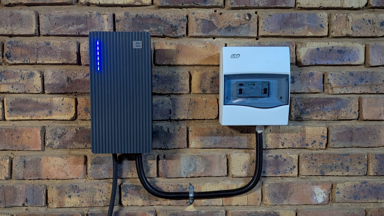 A TeltoCharge on a brick wall beside its DB box, with no load-control hardware between them